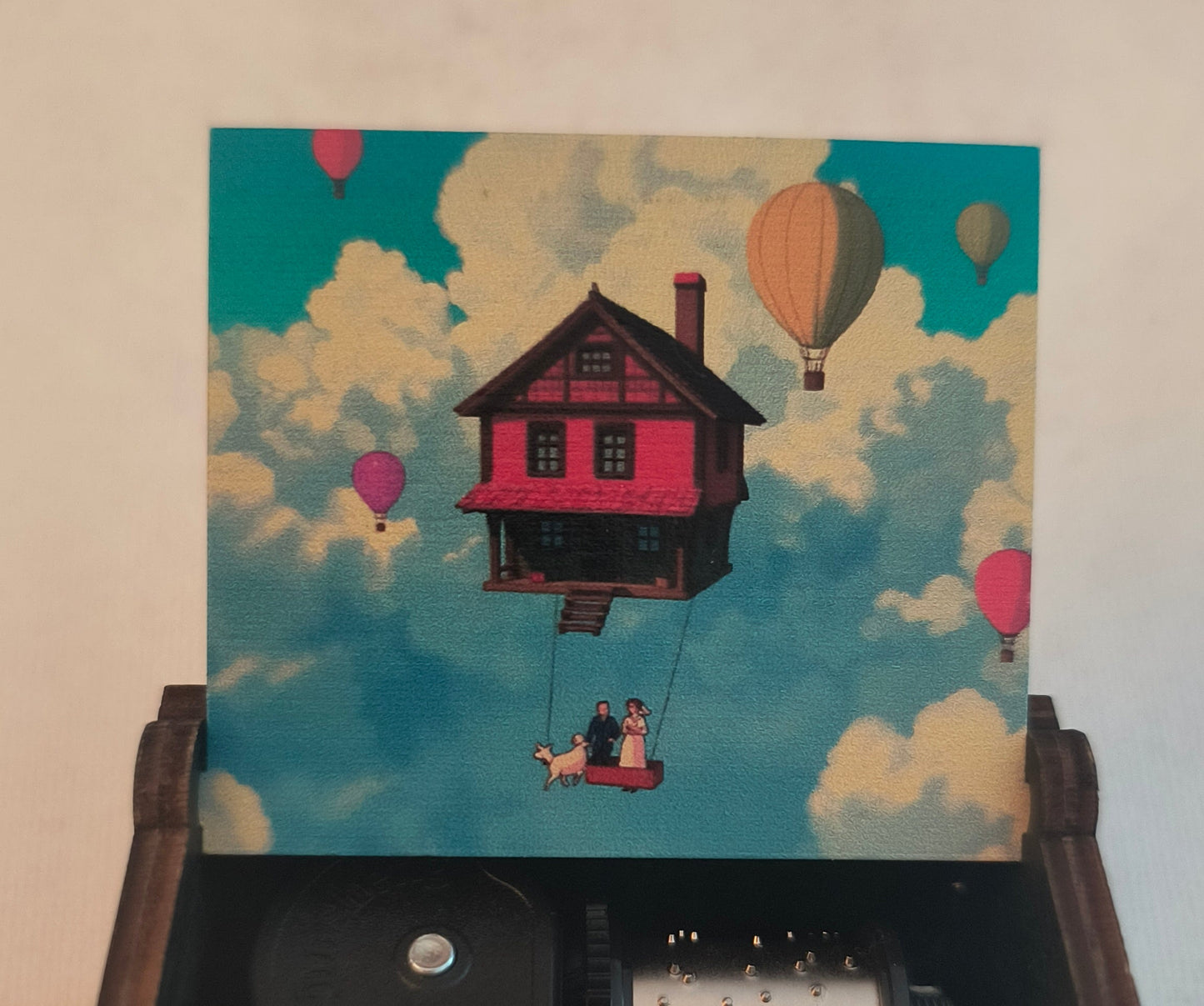 Wooden music box with mechanical components and a colorful illustration on the lid.