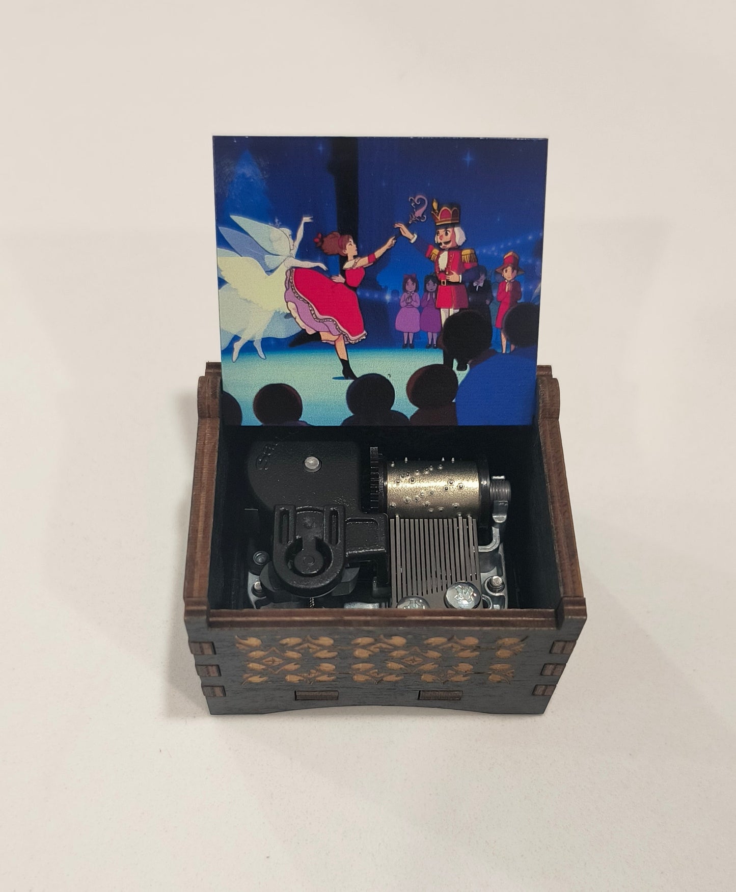 Wooden box with a vintage movie projector inside, featuring a colorful movie reel on a white background.