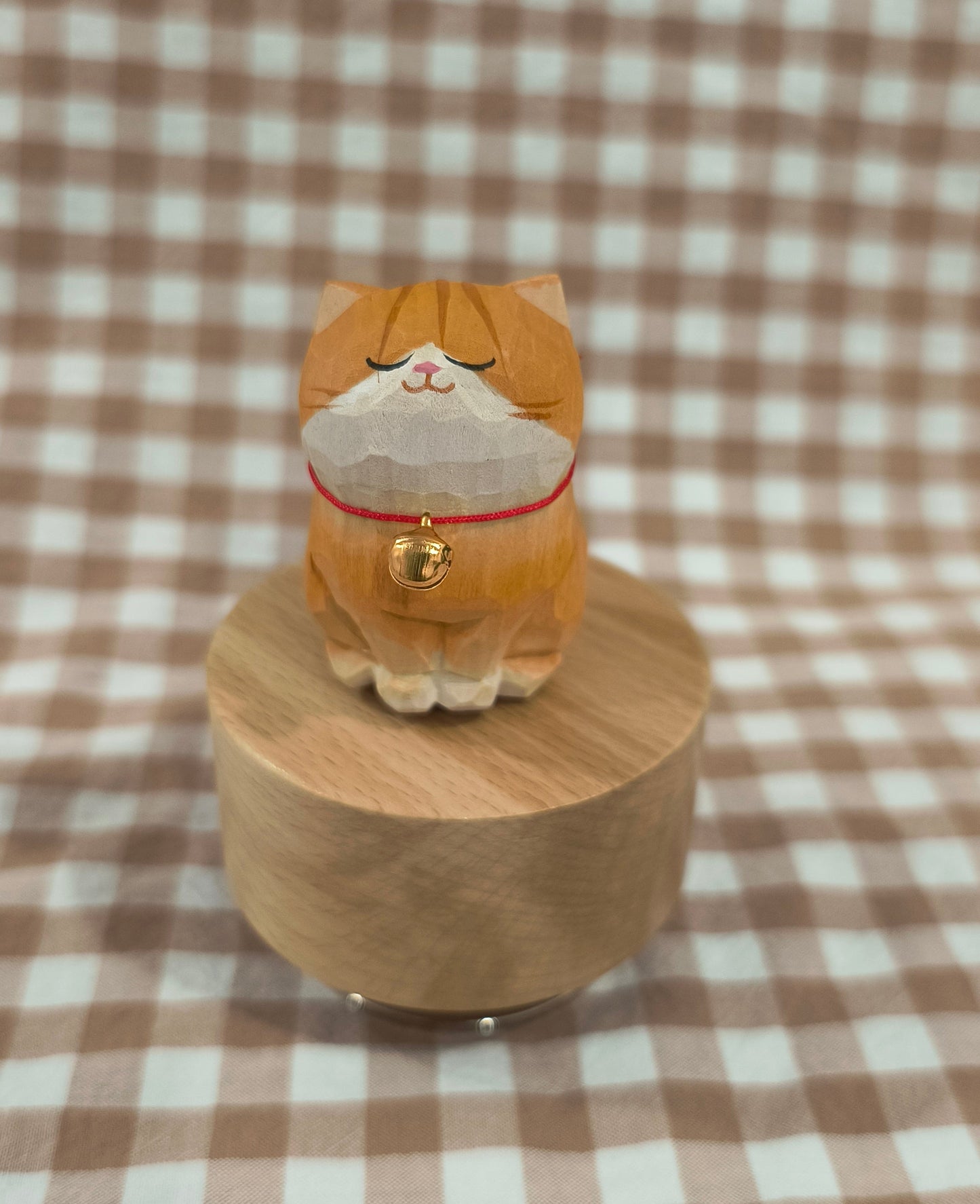Wooden cat figurine with a checkered brown and white background
