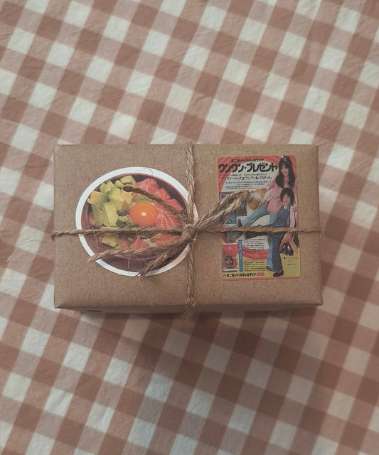 Small brown paper box with a colorful sticker on a checkered fabric background