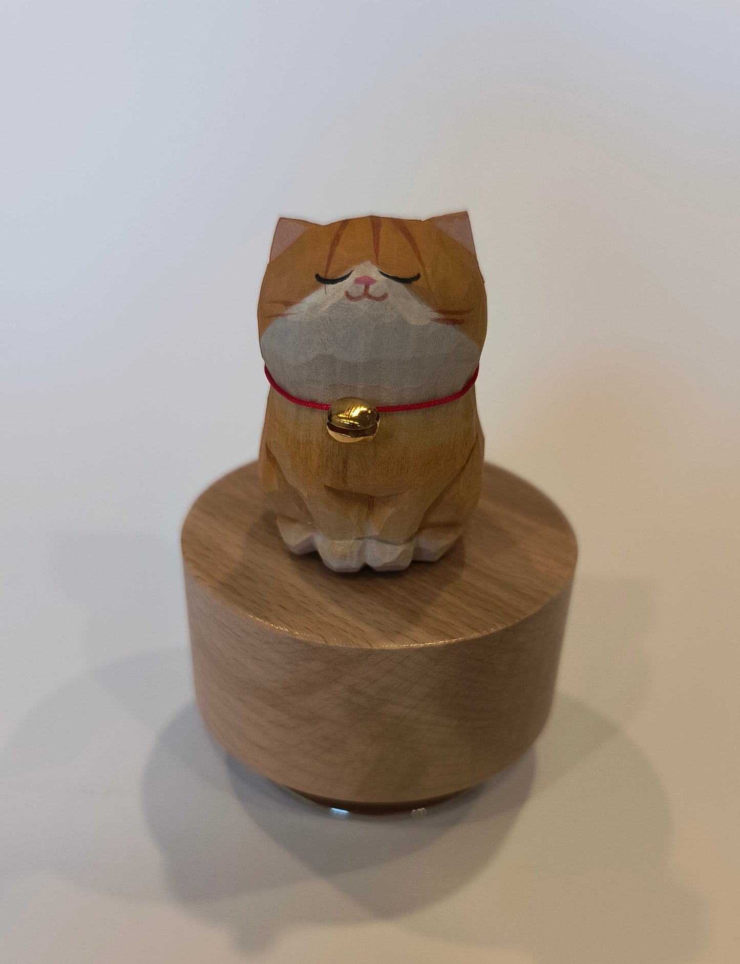 Wooden cat-shaped object with a bell on a white background