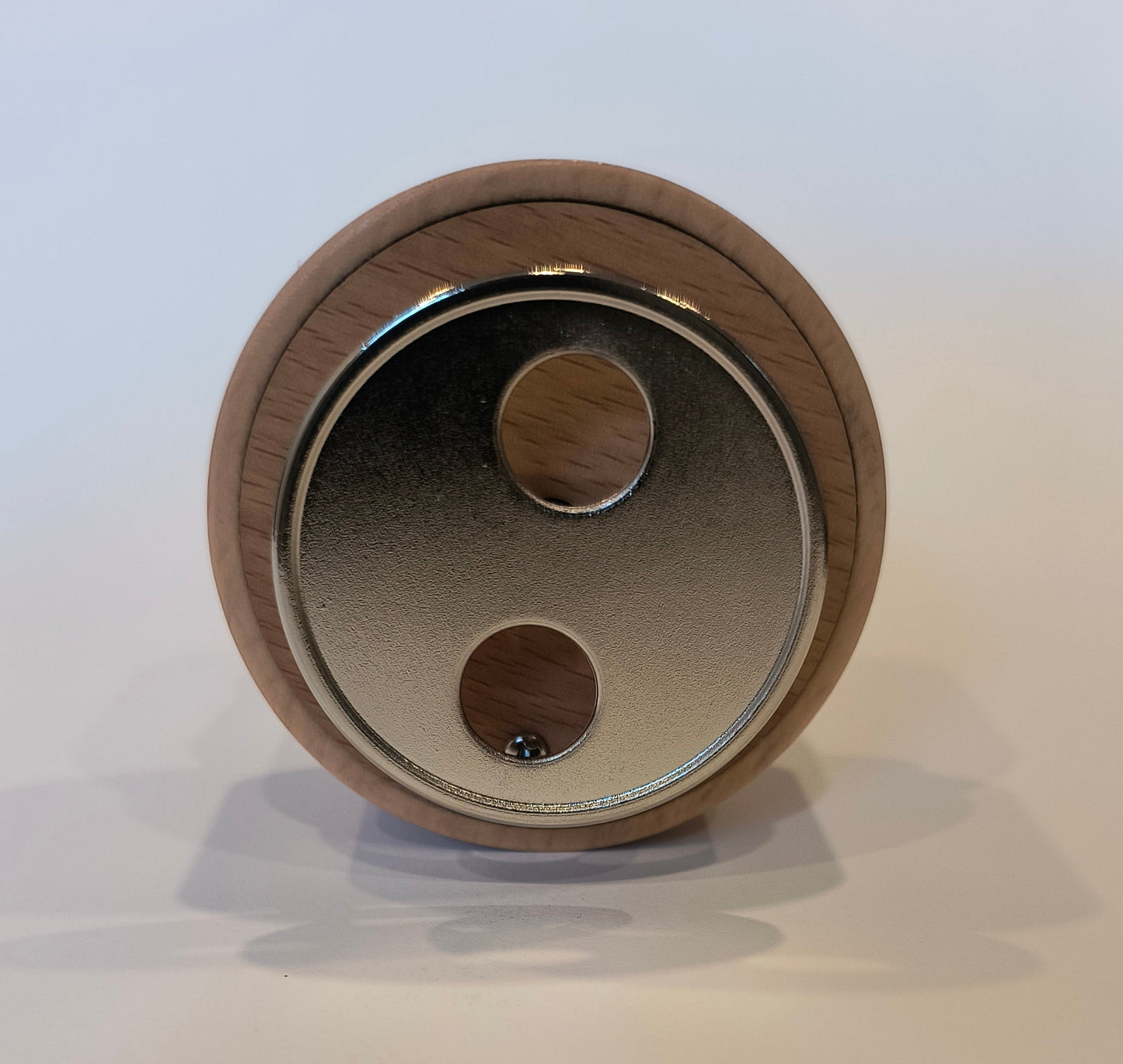 Close-up of a wooden circular object with metallic center on a white background