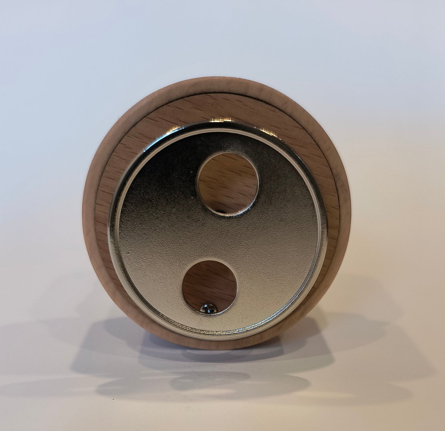 Close-up of a wooden circular object with metallic center on a light background