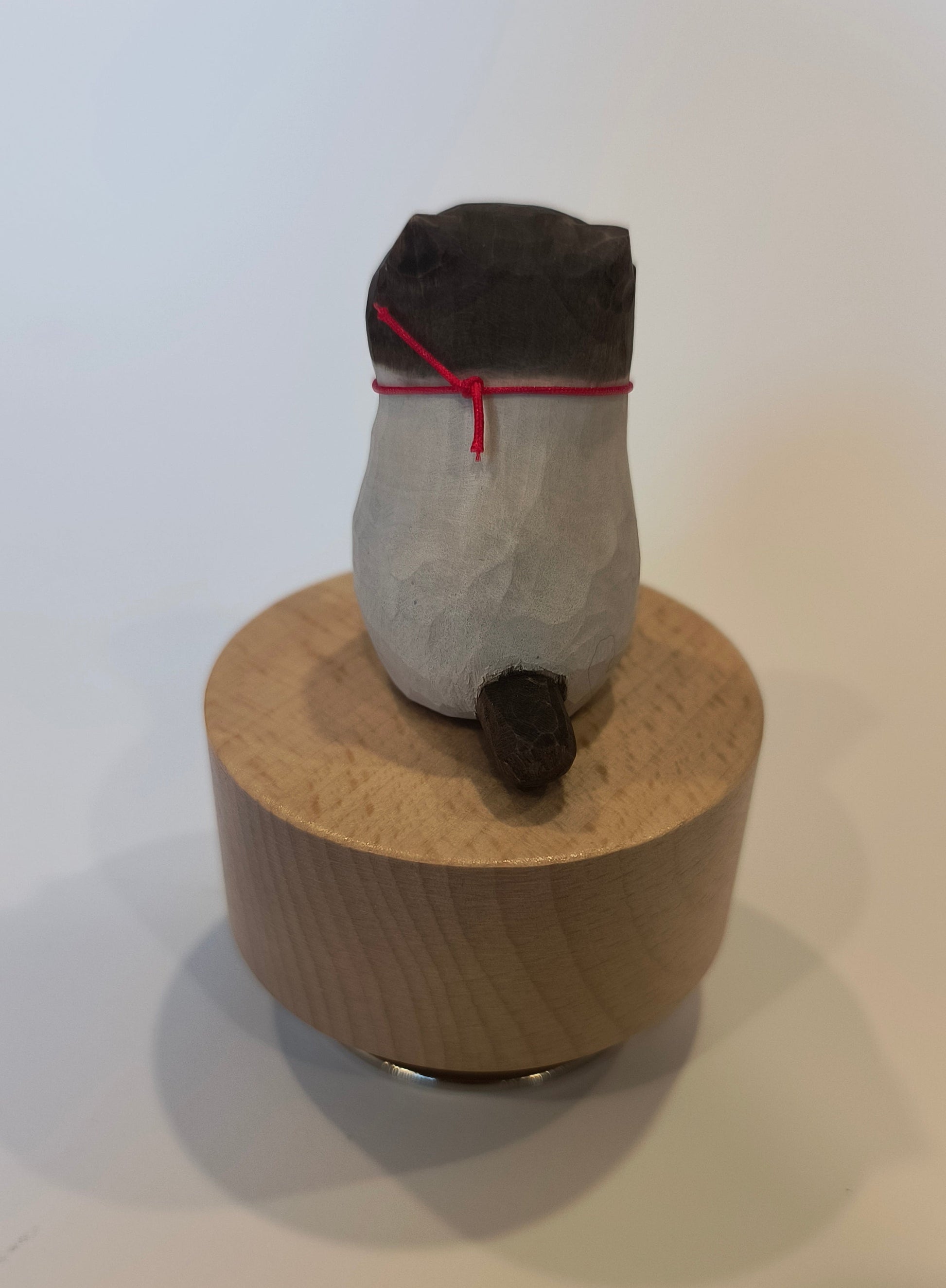Bottle wrapped in brown paper with black tape and red string on a white background