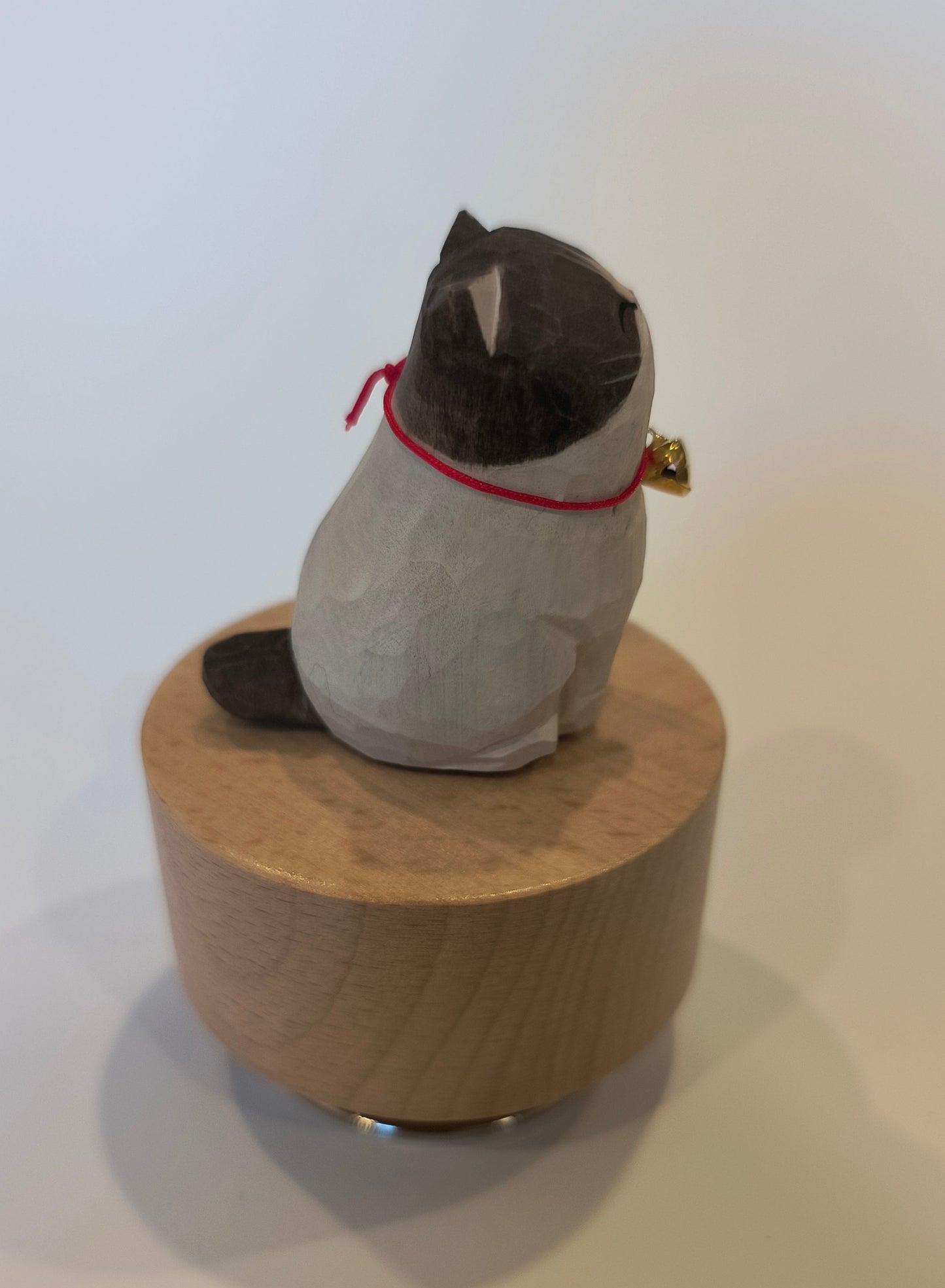 Small sculpture of a figure on a wooden block against a white background