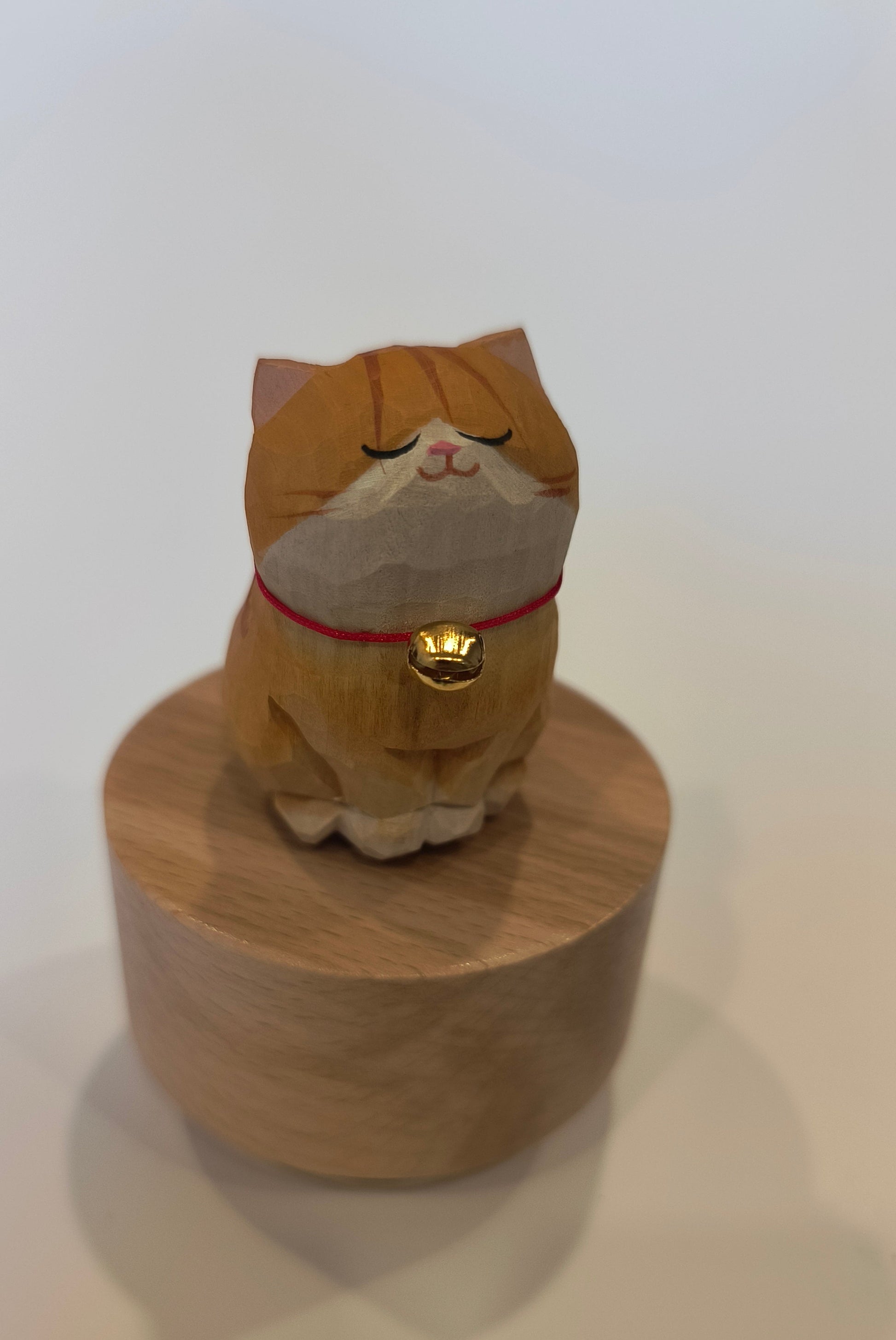 Wooden cat-shaped object with a red ribbon on a white background
