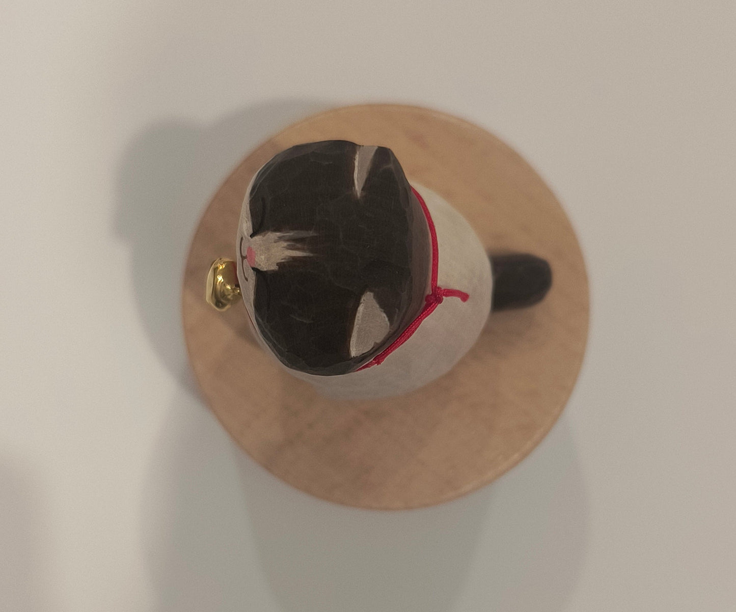 Small wooden spool with a black and white cat figure on a plain background