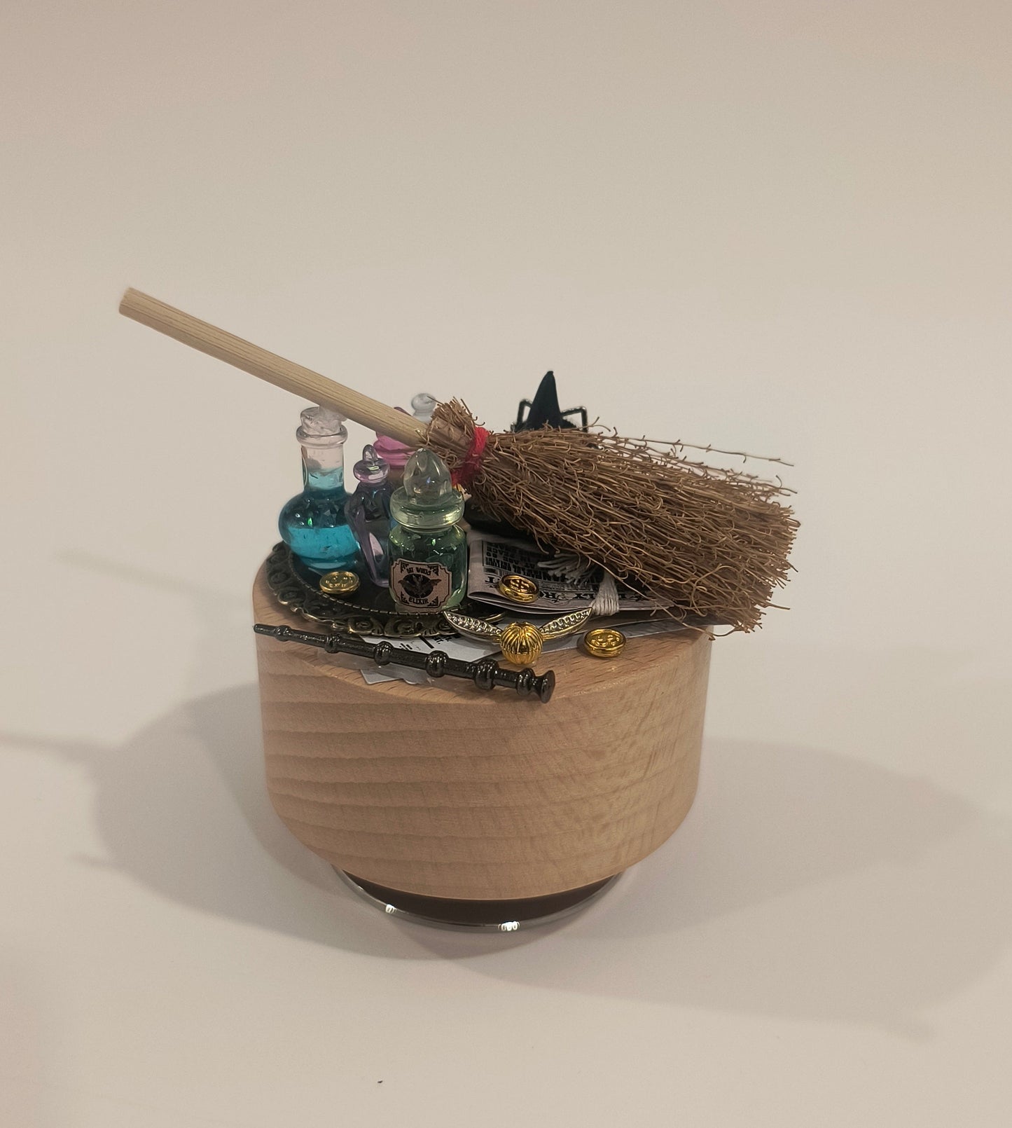 Decorative wall piece with a broom and various objects on a plain background