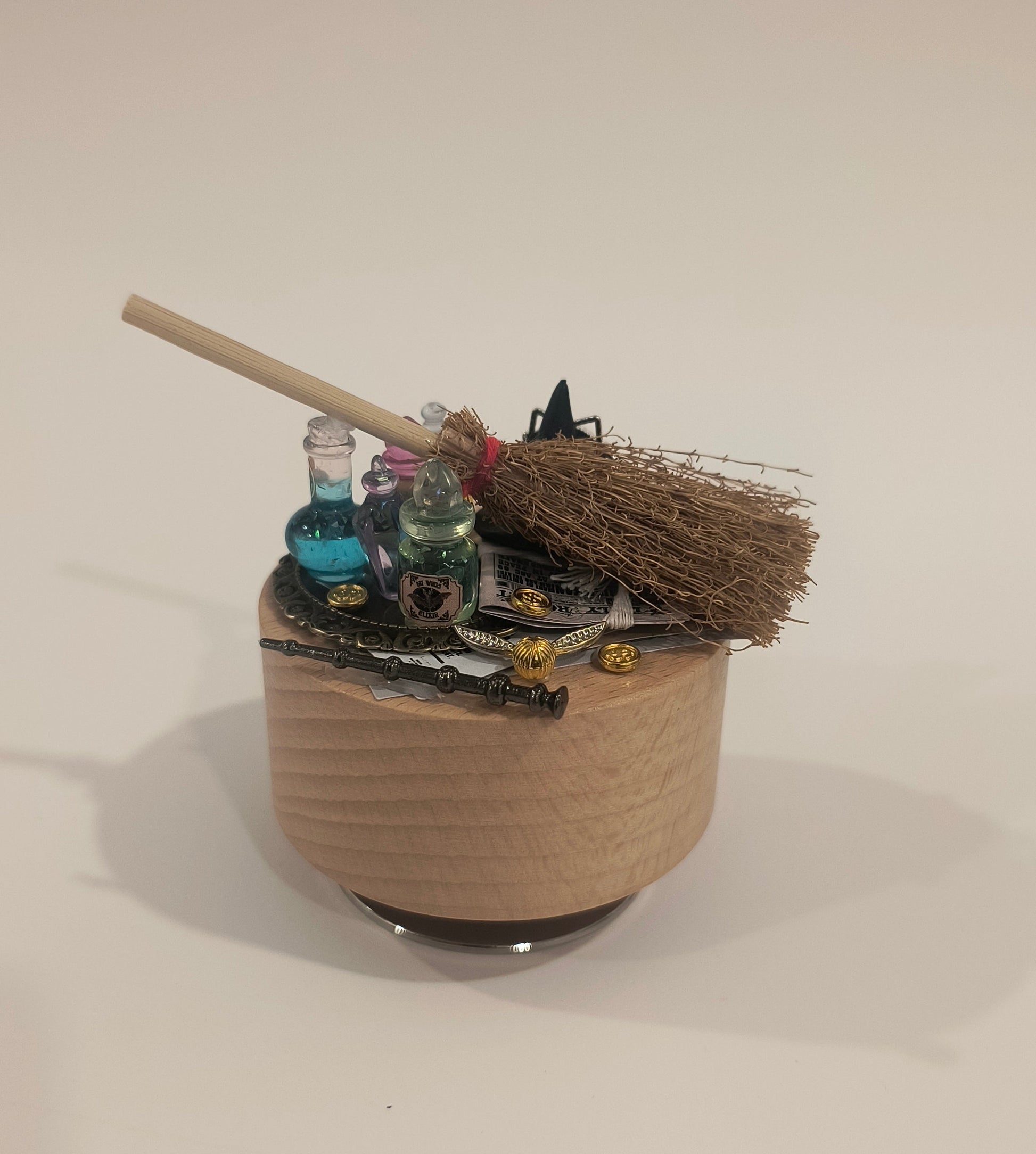 Decorative wall piece with a broom and various objects on a plain background