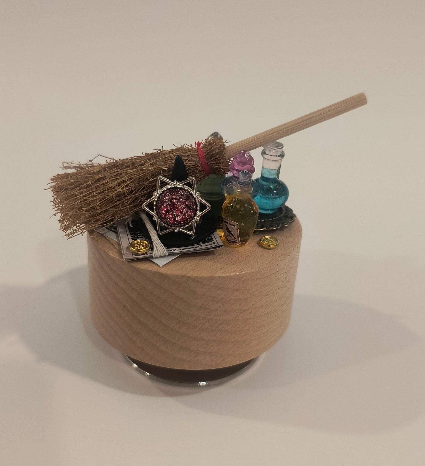 Decorative broom with colorful pins on a cardboard tube against a plain background