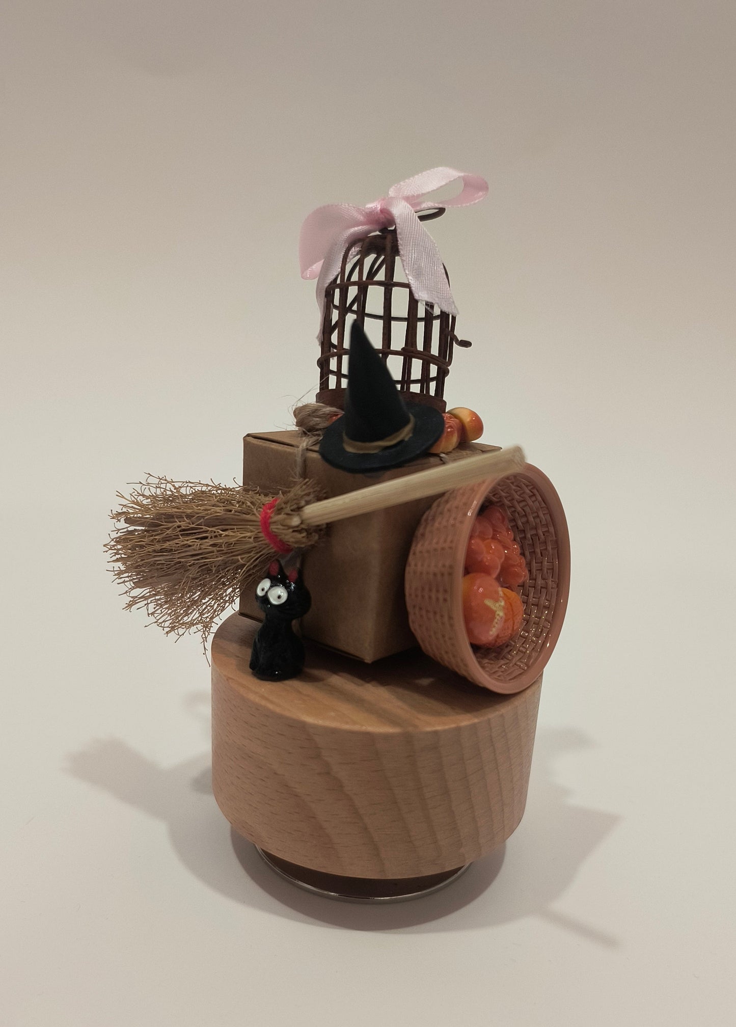 Halloween-themed decoration with a broom, basket, and pumpkins on a white wall.