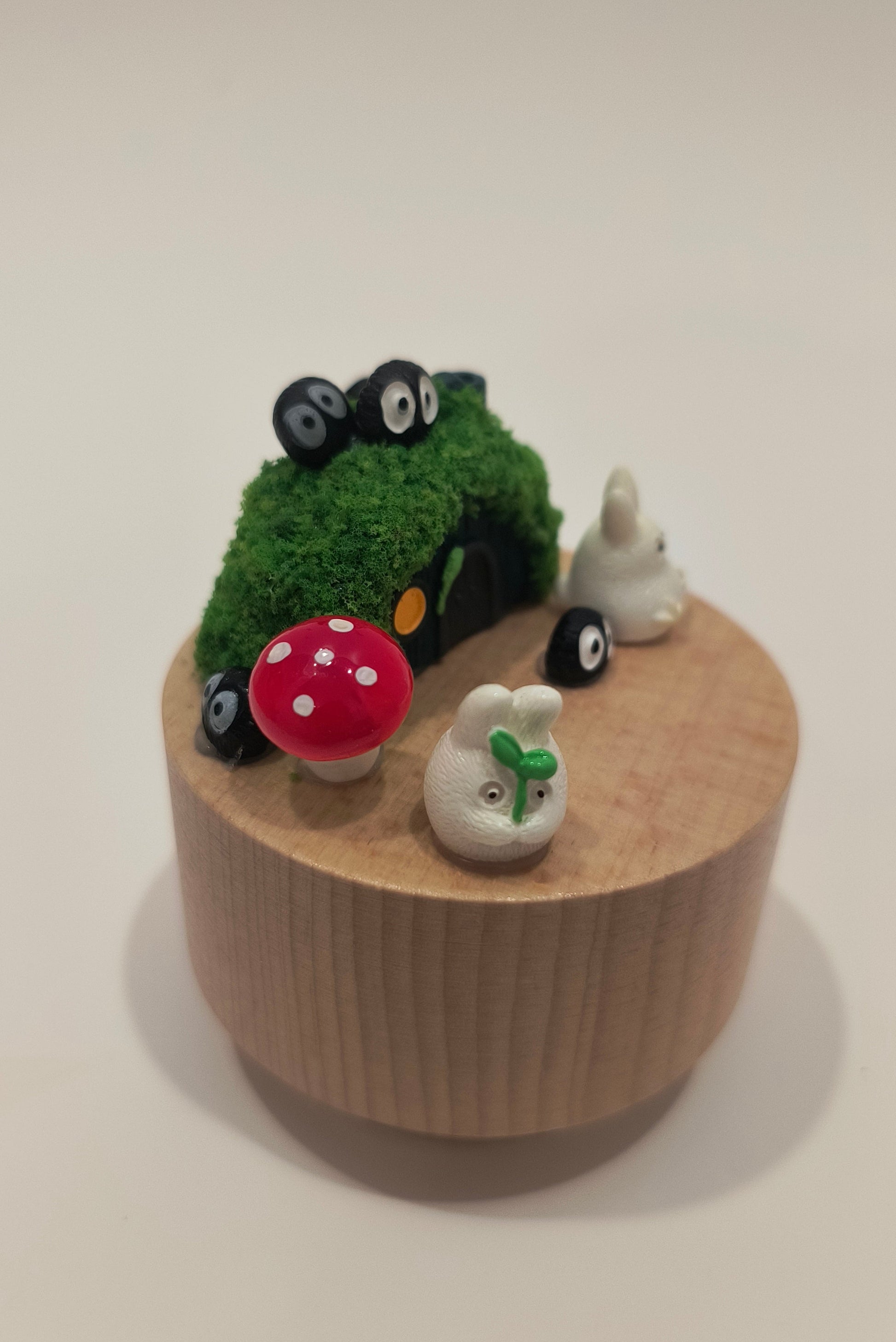 Decorative item with a small car, mushroom, and sheep figure on a beige base.