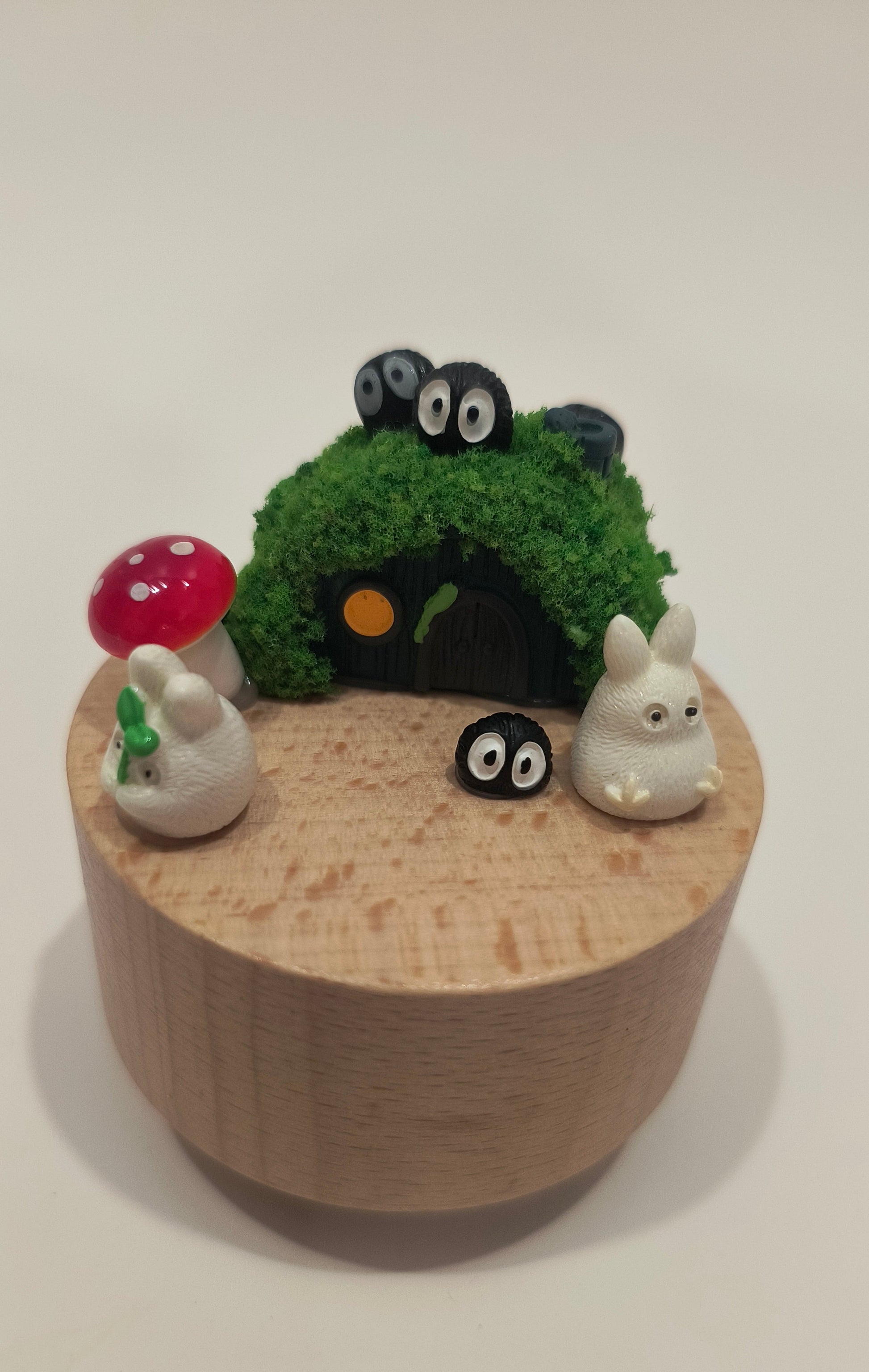 Wooden box with small animal figurines and a green plant on a white background