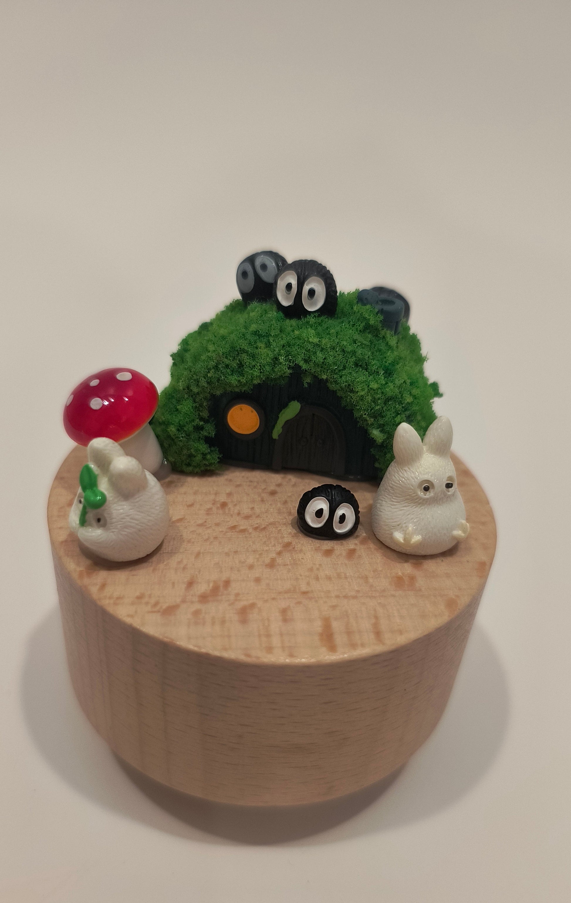 Wooden toy with animal figurines and a green bush on a beige background