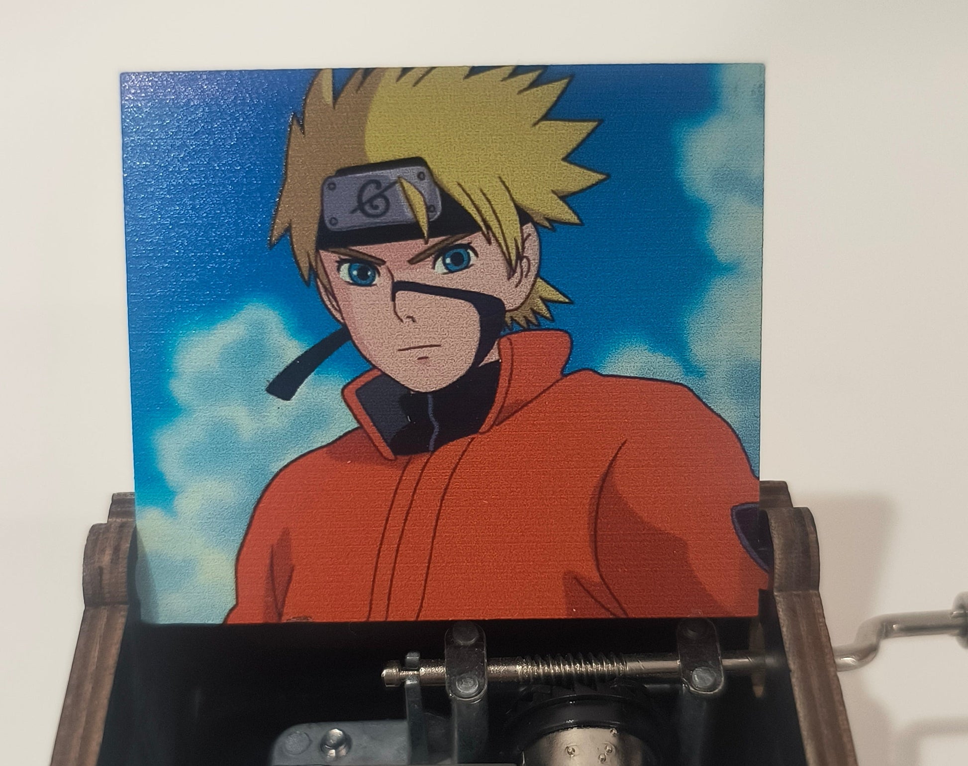 Wooden box with mechanical components and a colorful illustration of an anime character on a blue background.