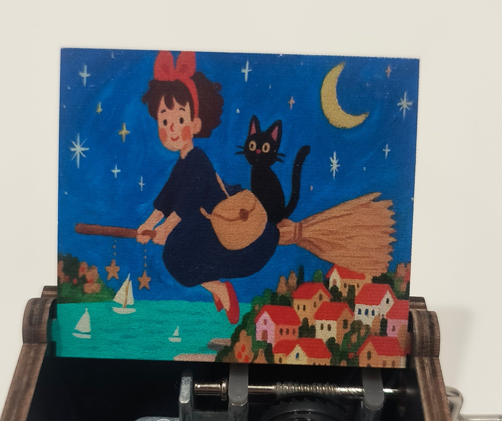 Music box with open lid revealing mechanical components and a colorful illustration on a white background