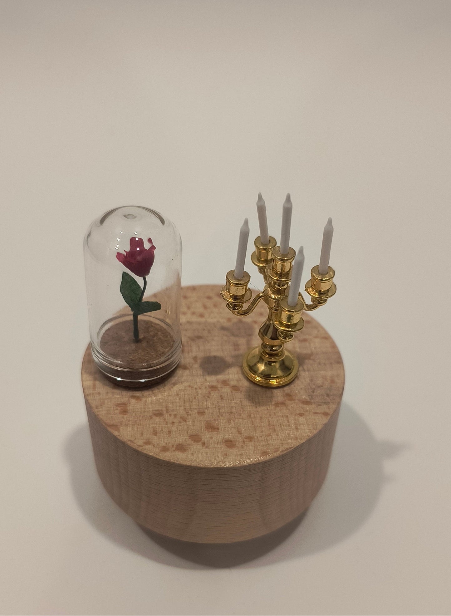 Decorative item with a small glass container and gold accents on a beige background