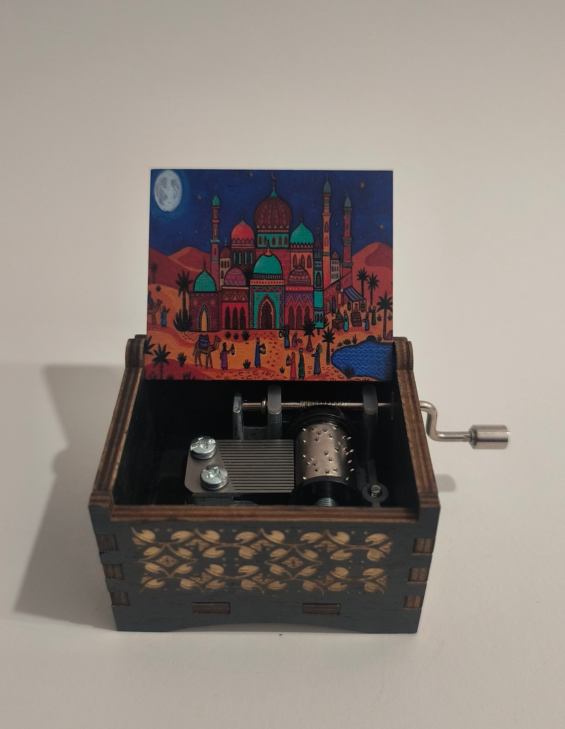 Decorative wall-mounted box with intricate design and mechanical elements on a plain background. Aladdin music box