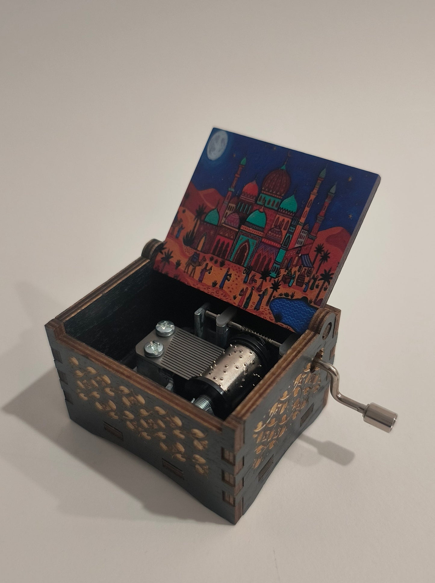 Decorative wooden music box with intricate designs on a plain background