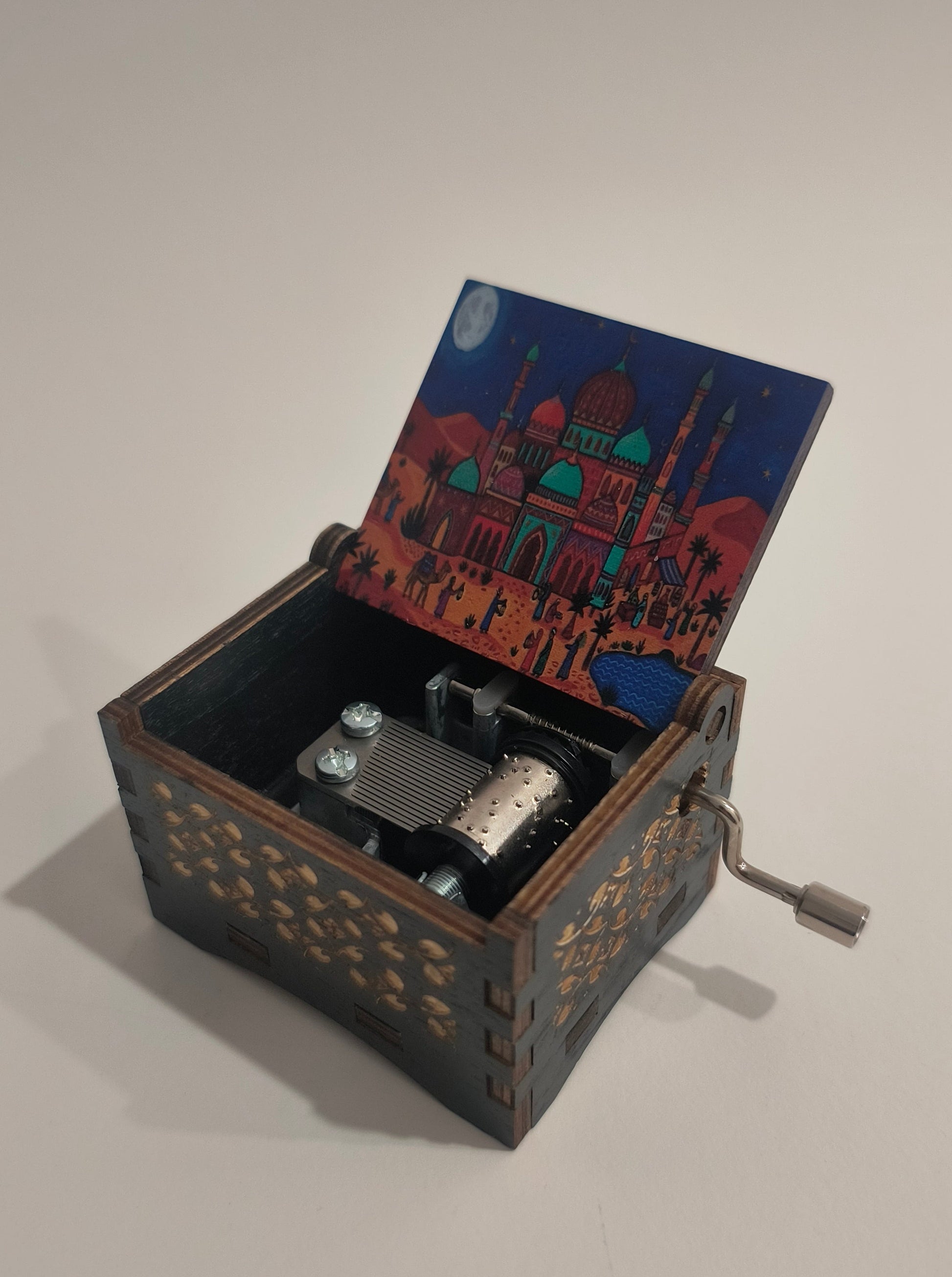 Decorative wooden music box with intricate designs on a plain background