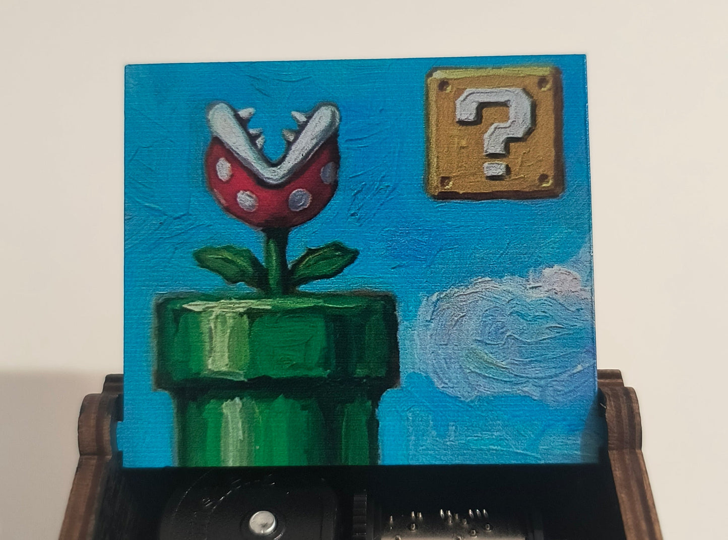 Wooden music box with a painted lid featuring a mushroom and flower design, on a beige background.